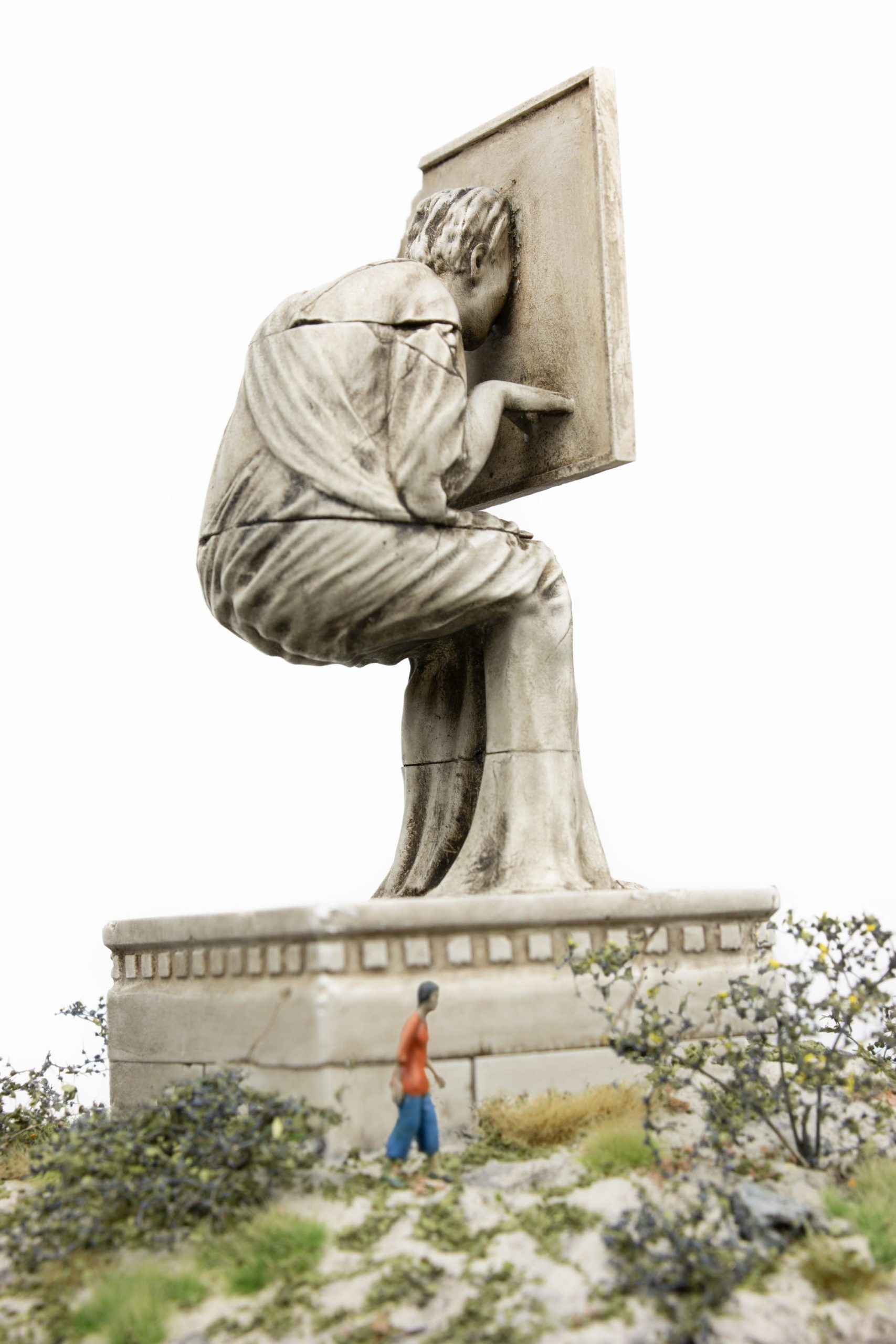 a small figure looks up at a statuesque figure hunched over with their face half inside a screen
