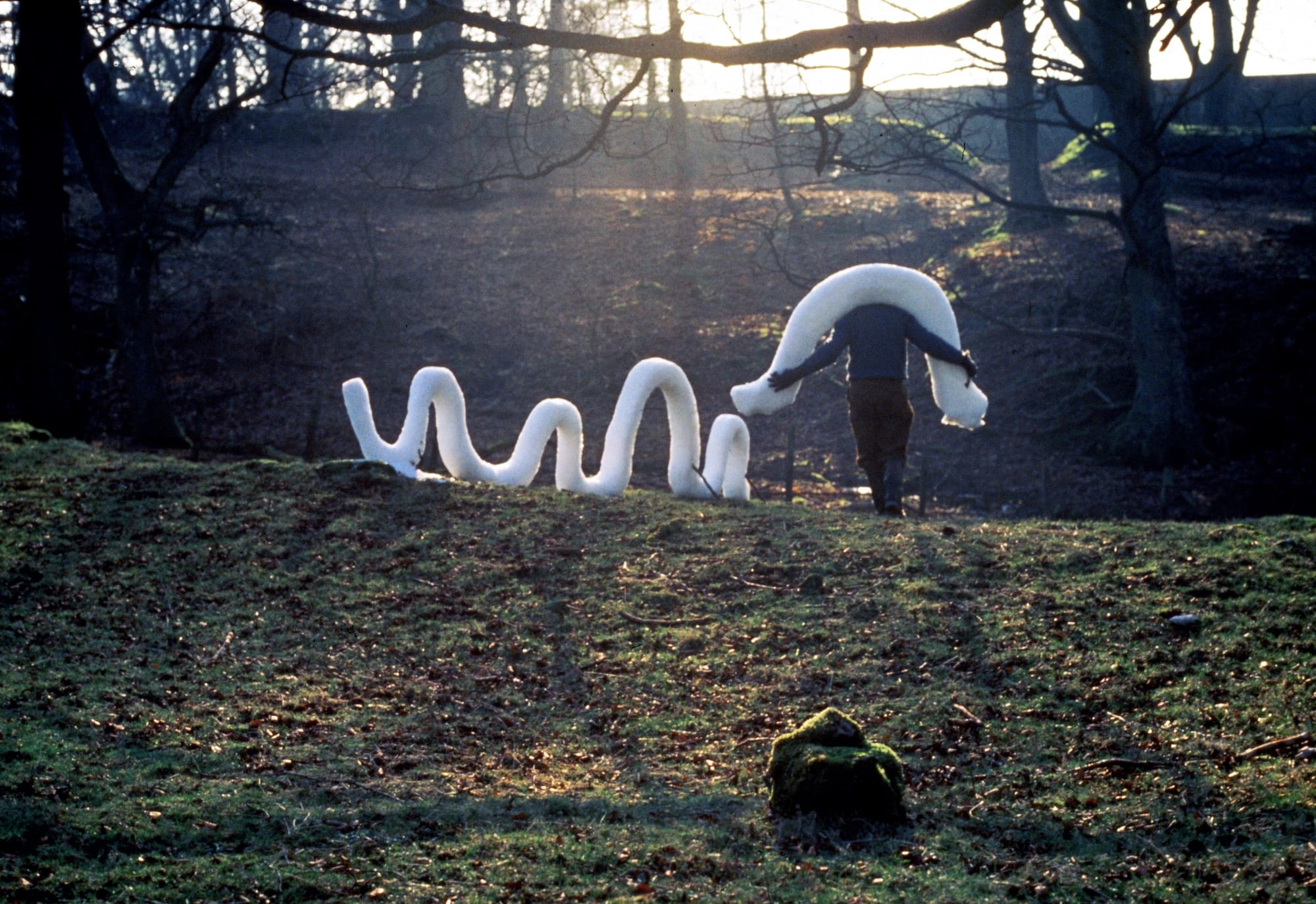 a photograph by Andy Goldsworthy showing the artist carrying carved chunks of snow around the countryside