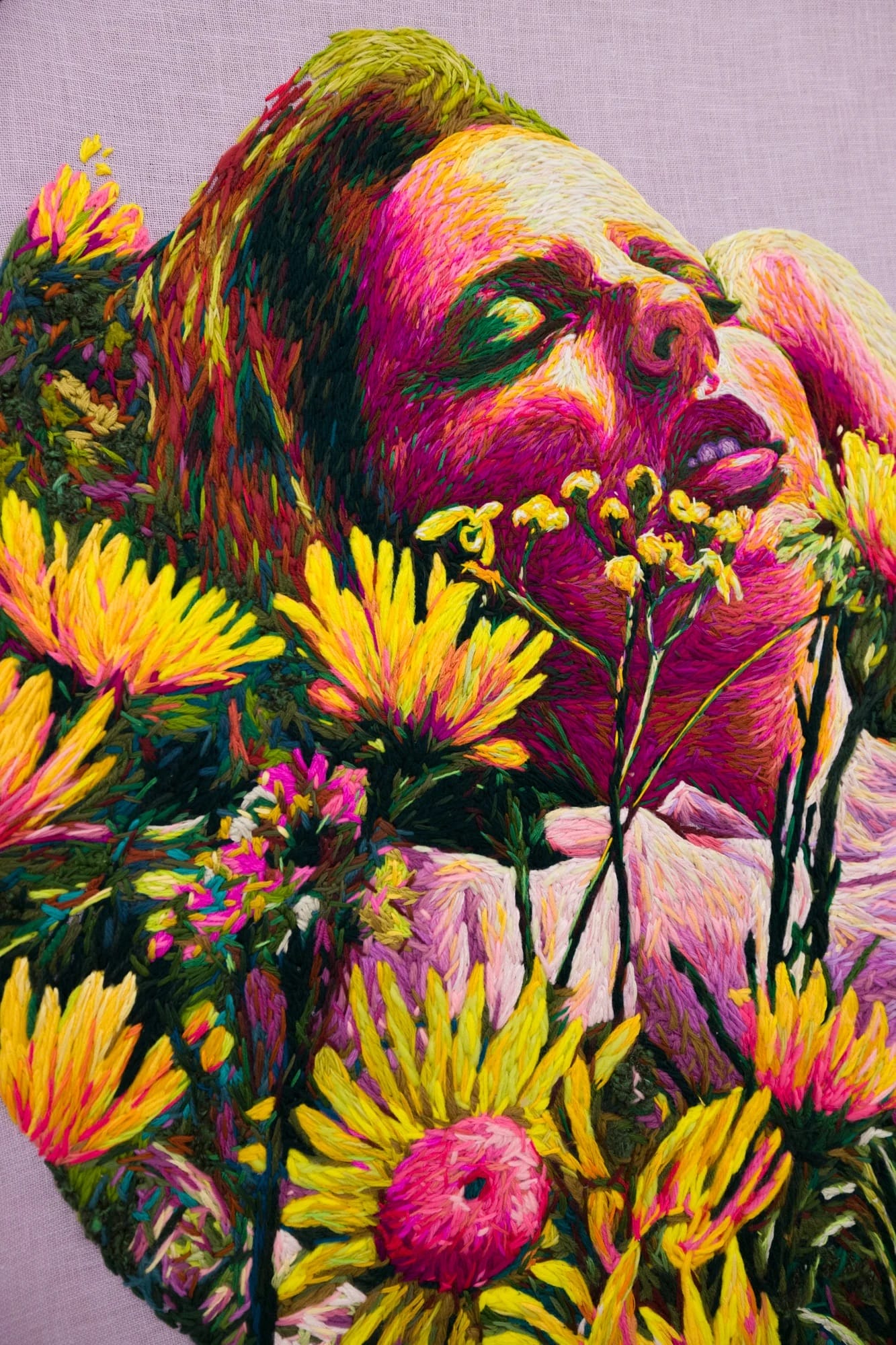 a detail of a crewel embroidery piece by Danielle Clough of a woman lounging amid some flowers