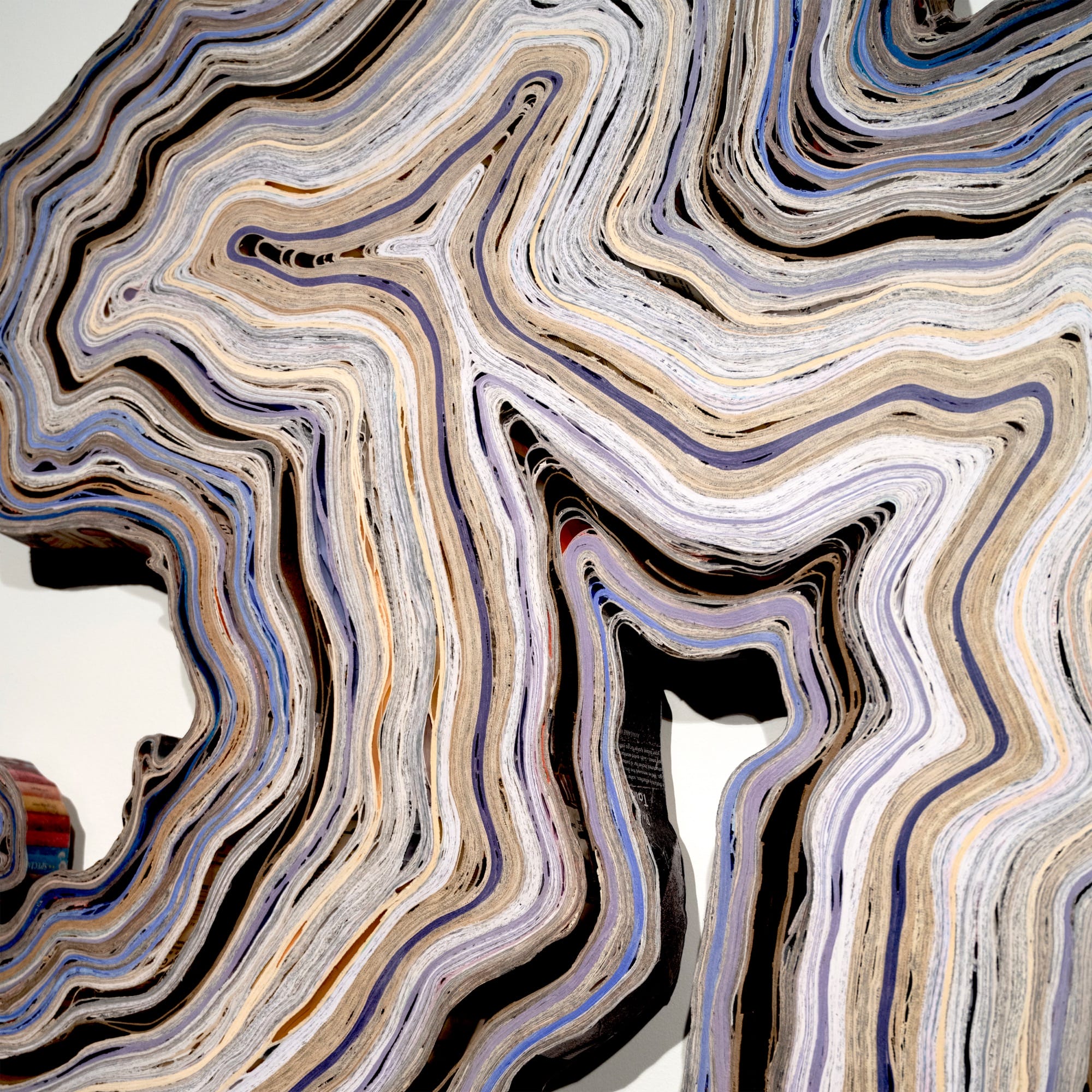 a detail of an abstract wall artwork by Jessica Drenk using repurposed junk mail in curving forms that loosely resemble an agate