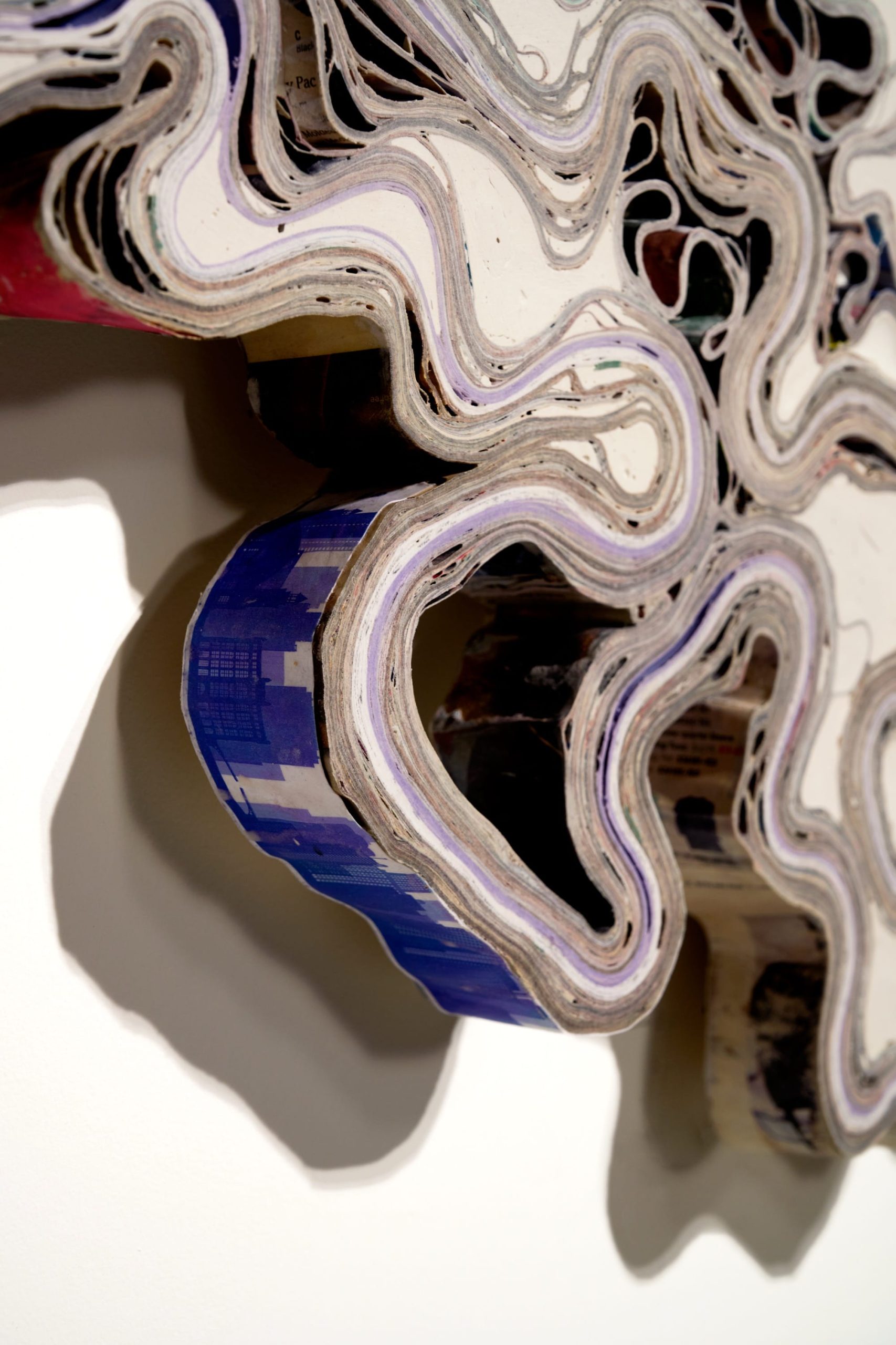 a detail of an abstract wall artwork by Jessica Drenk using repurposed junk mail in curving forms