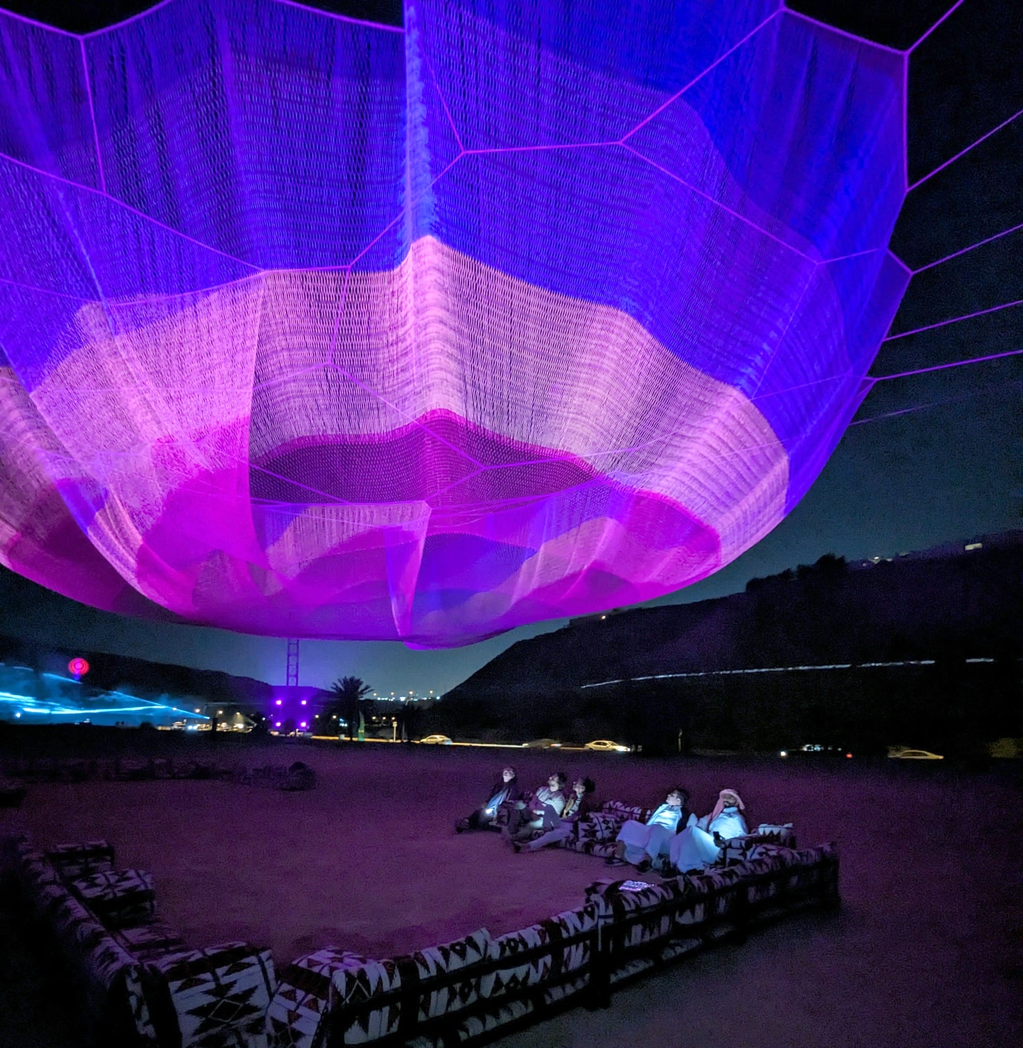 a purple and pink Janet Echelman installation suspended in the air