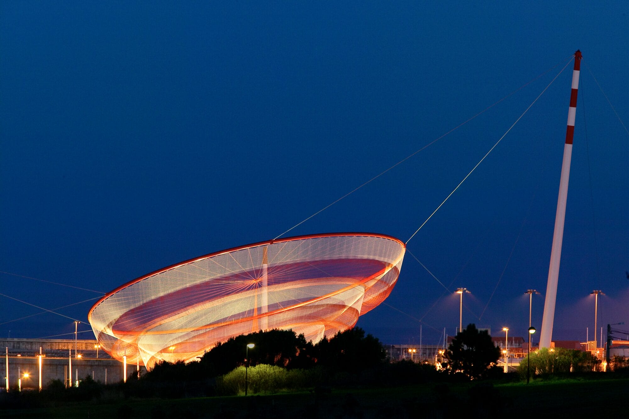 an orange and pink Janet Echelman installation suspended in the air
