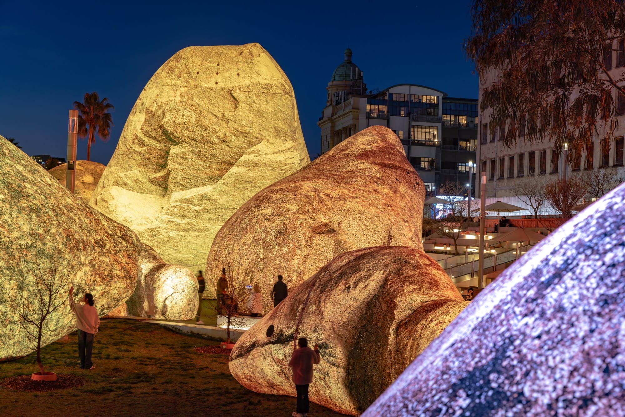 people stand between massive inflatable rocks glowing in yellow