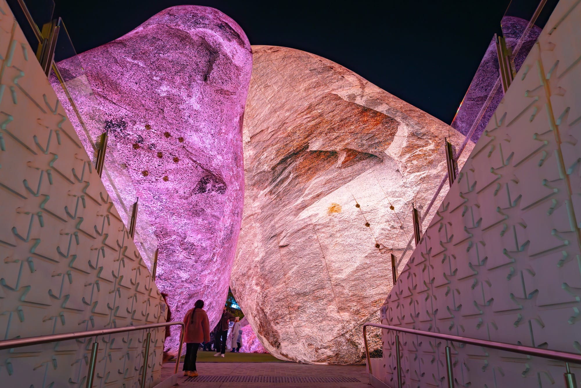 people stand between massive inflatable rocks glowing in pinks