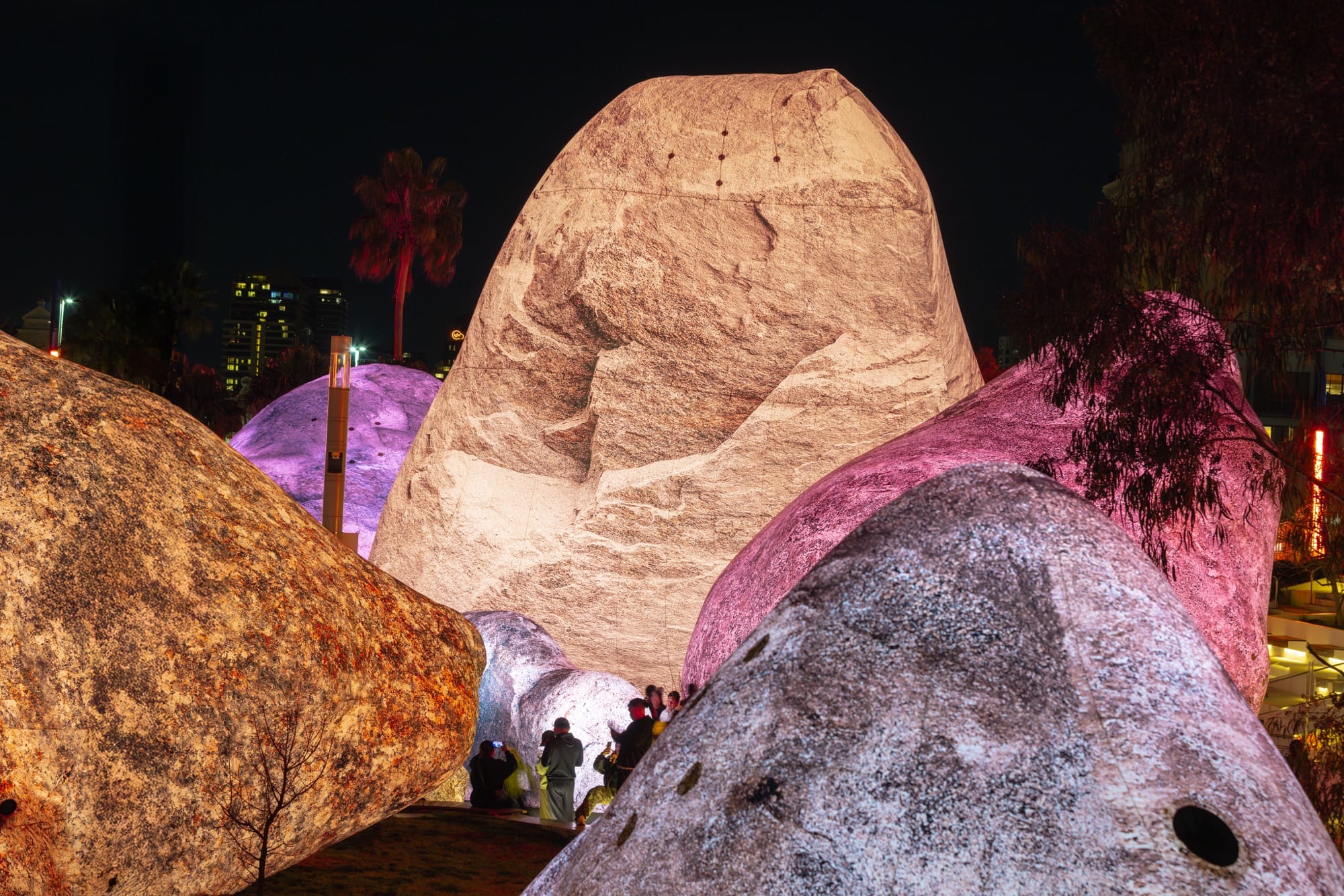 people stand between massive inflatable rocks glowing in pinks