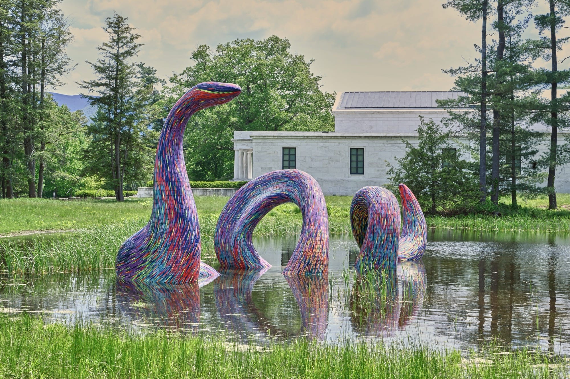 a sculpture of a colorful serpent by Javier Senosiain in a pond