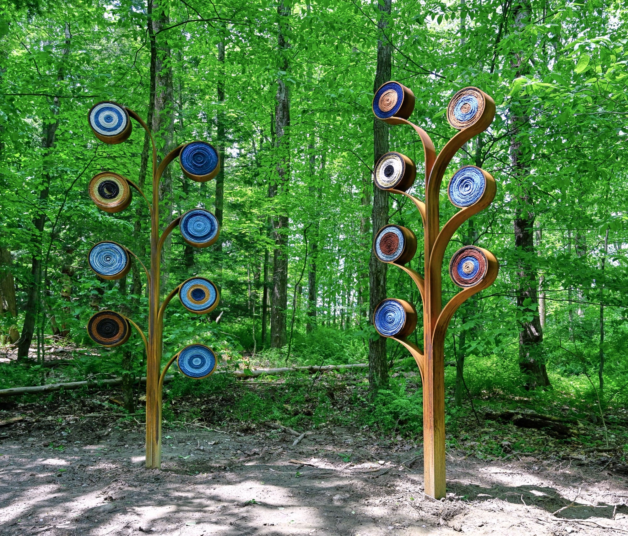 two abstract tree forms installed in a wooded area, by artist Aboubakar Fofana, with dyed fiber elements