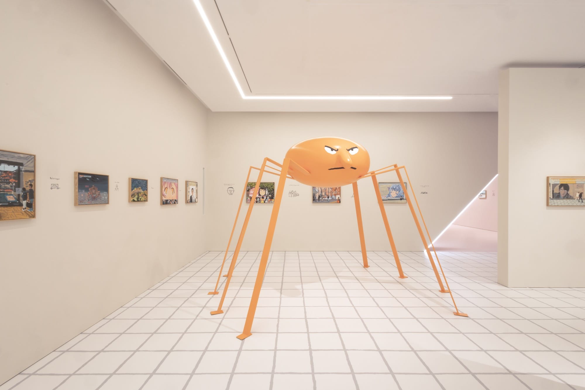 a large orange spider sculpture with an angry in a gallery with small works on the wall