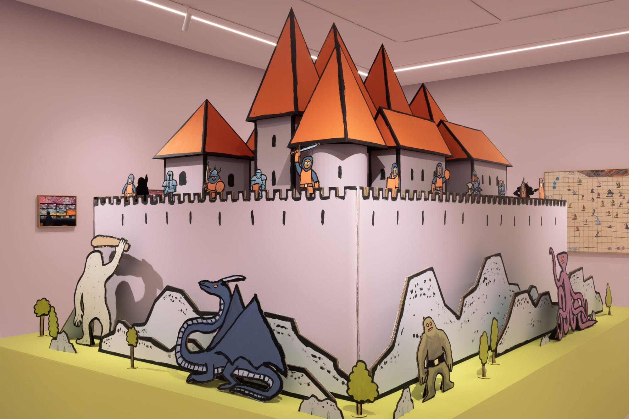a castle sculpture with cartoonish characters around the base of the wall