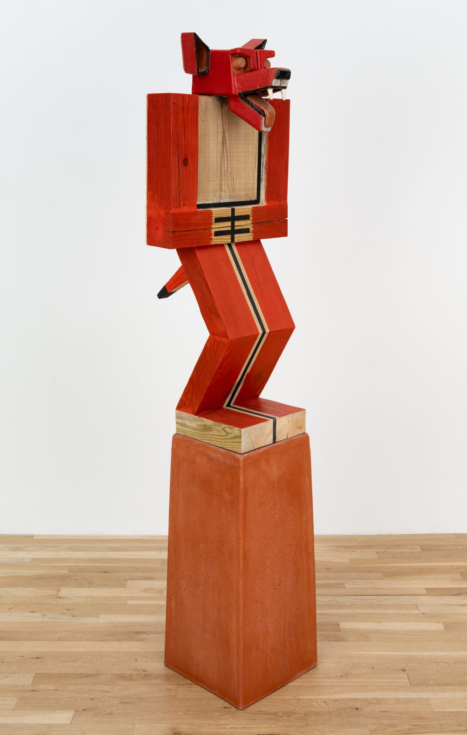 a sculpture by Steve Keister of a blocky, cartoonish red coyote-man on a pedestal