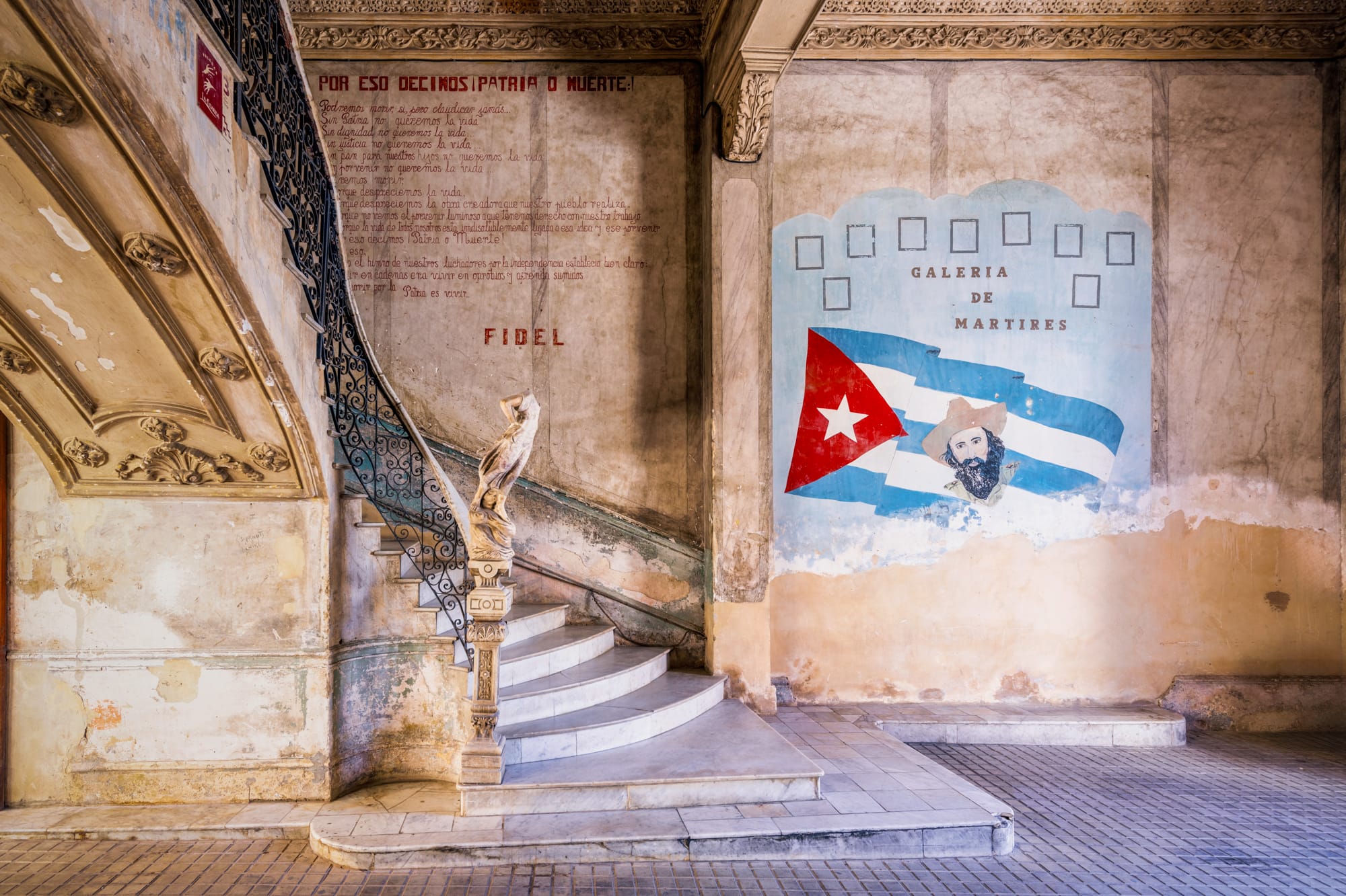 a photograph by James Kerwin of a stairwell with a painting of the Cuban flag on the wall