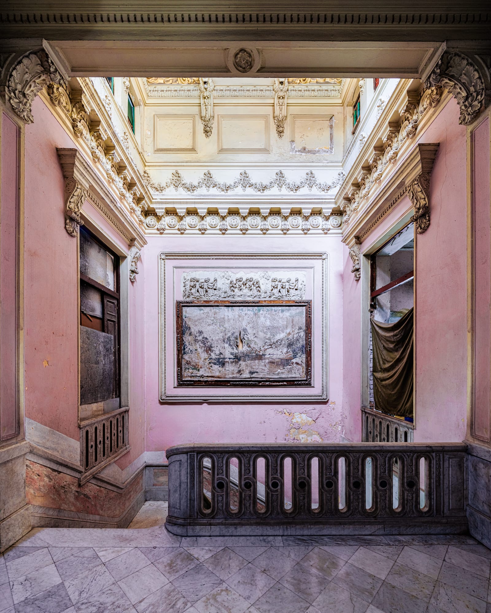 a photograph by James Kerwin of an elegant, dilapidated interior in Cuba, with pink walls and artwork