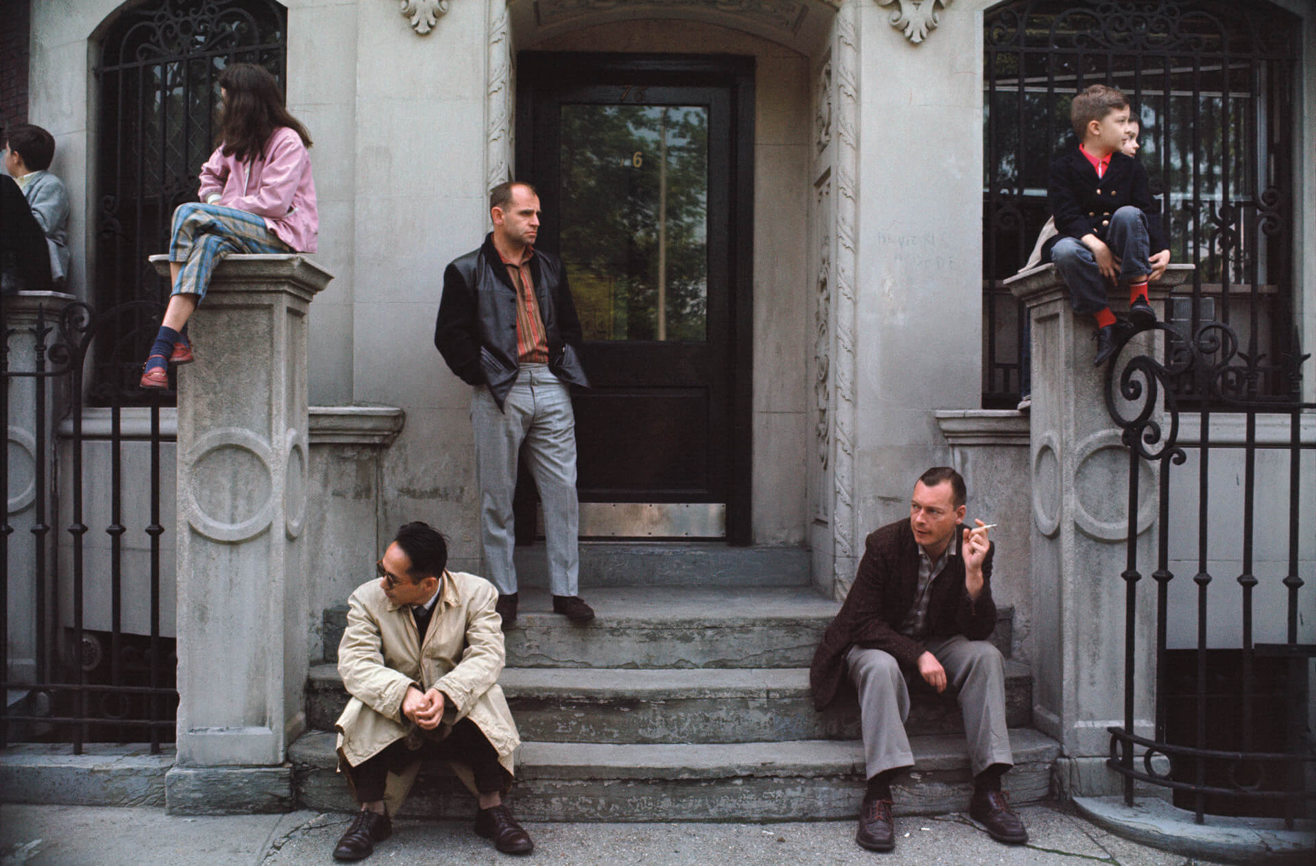 A photo by Joel Meyerowitz of people sitting on a New York City stoop