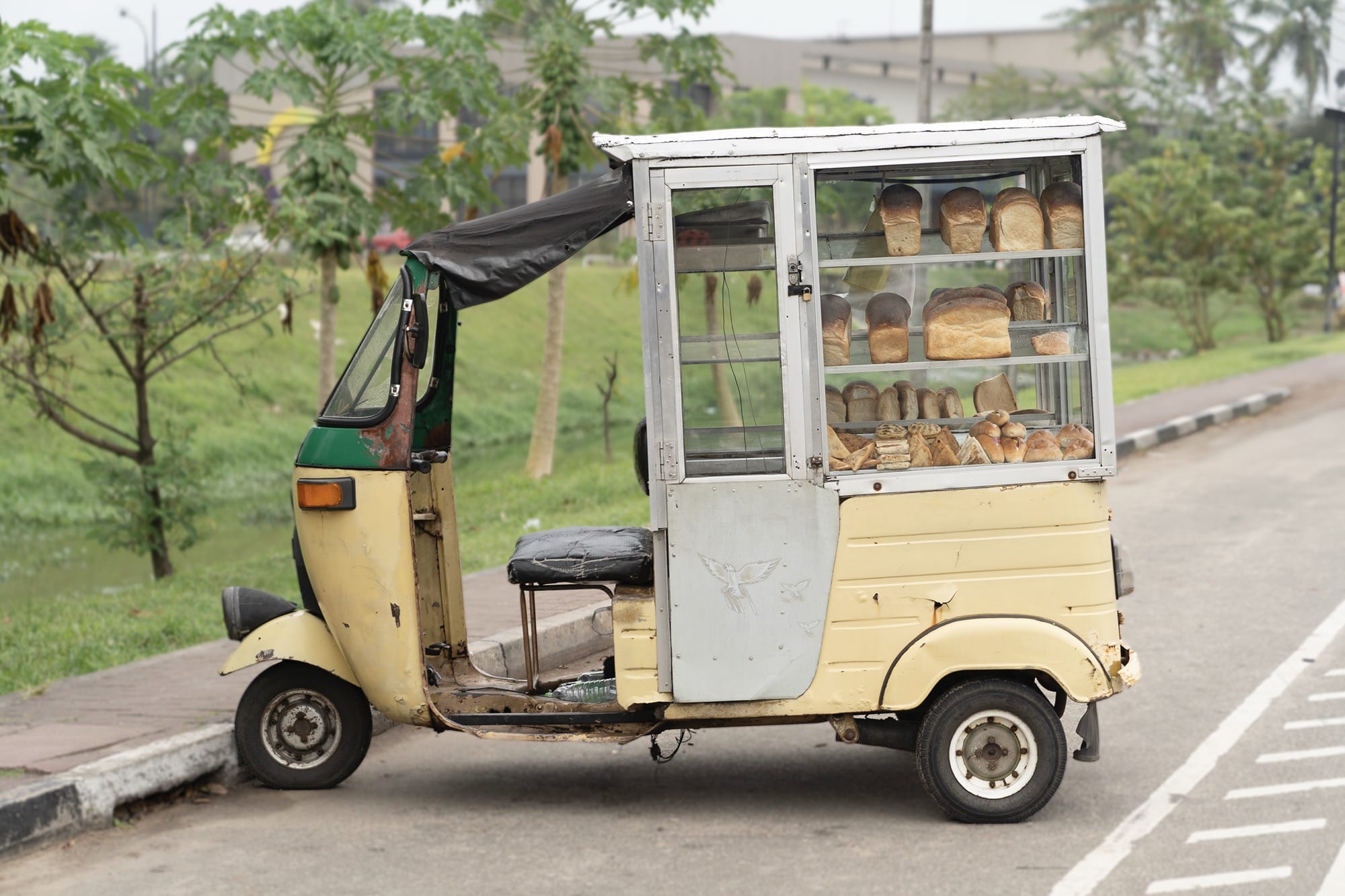 a small tuk vehicle with shelving and breads in the back