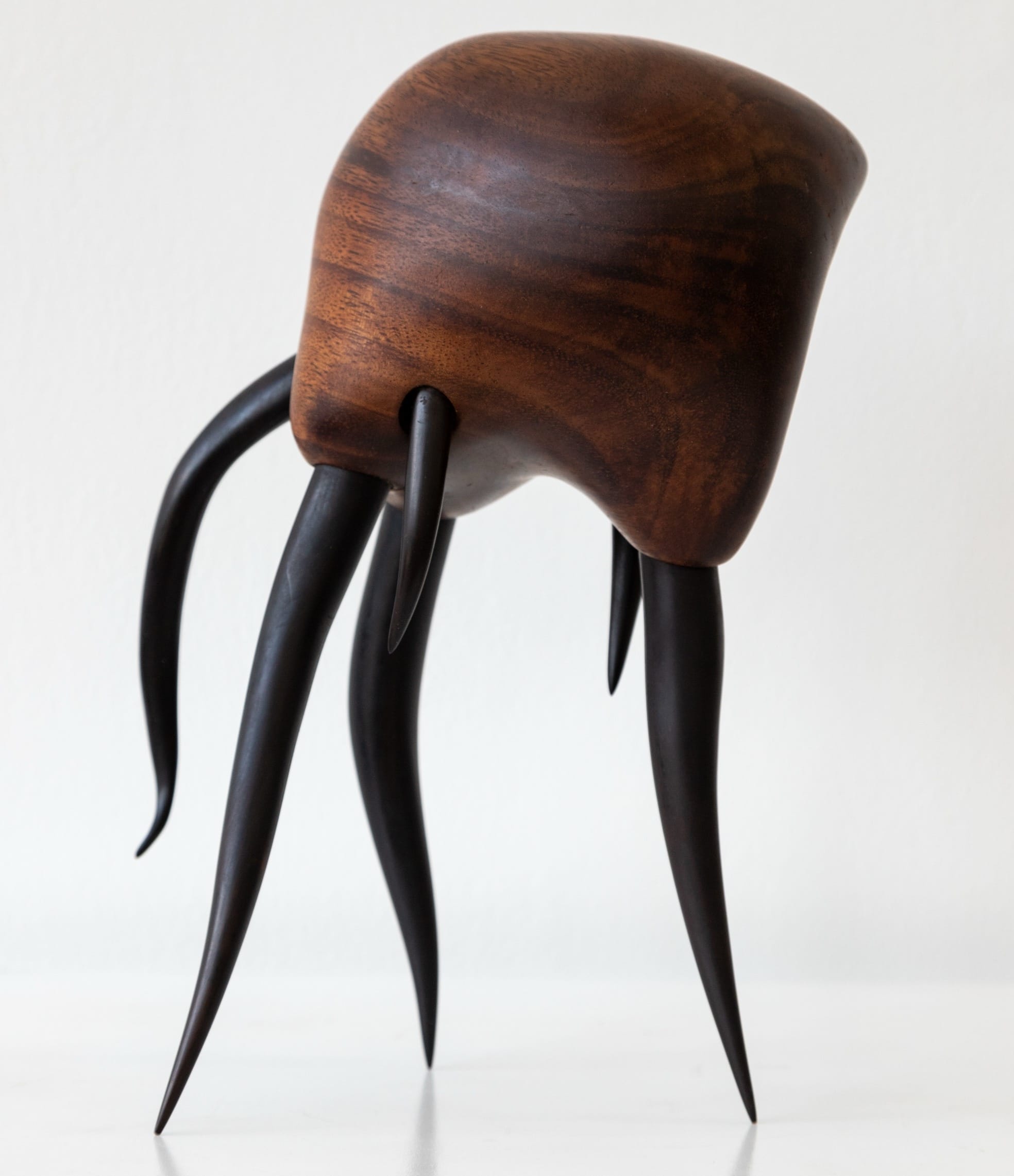 a wooden sculpture by Donald Wasswa with an abstract, sea creature-like form with long tentacles