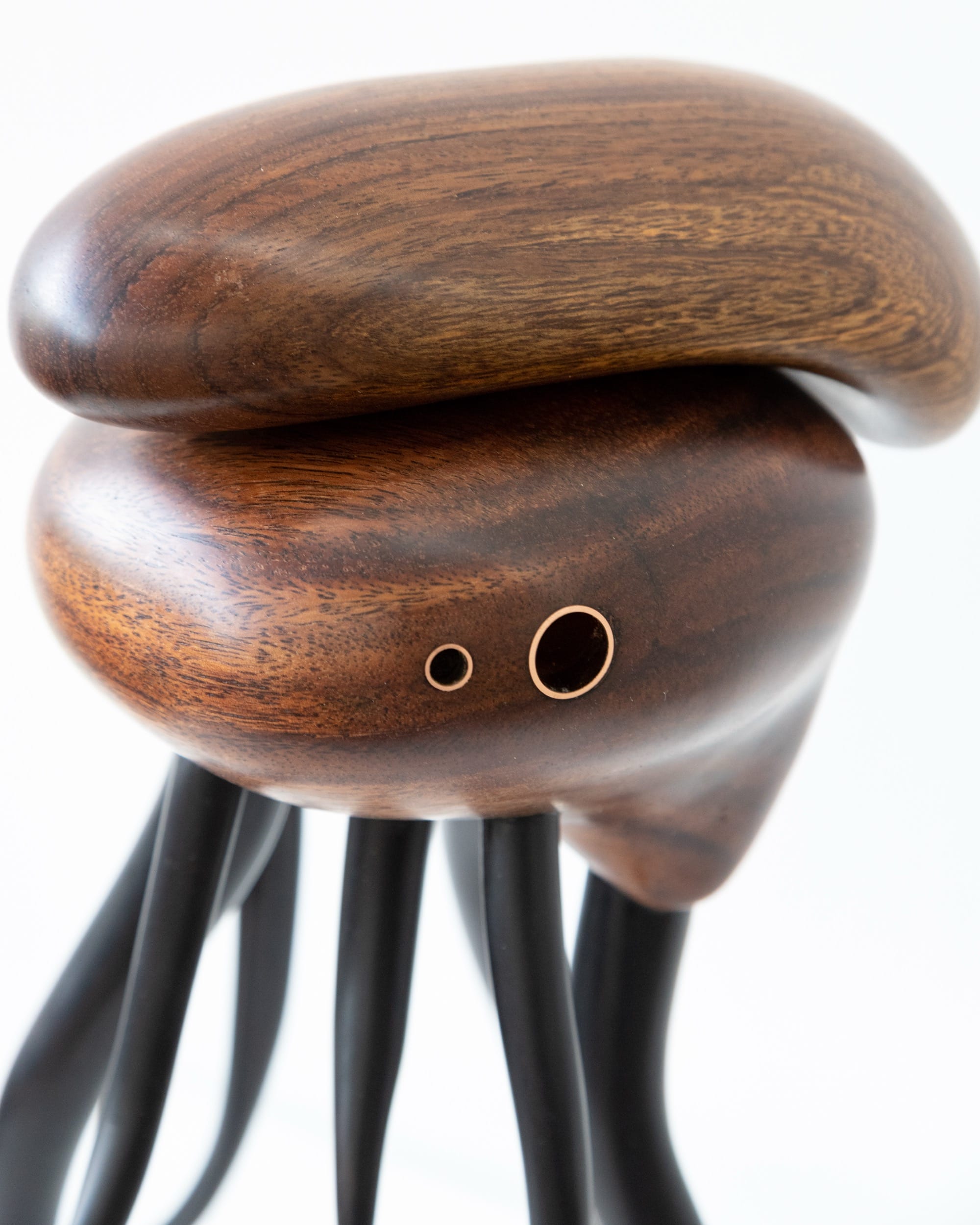 a wooden sculpture by Donald Wasswa with an abstract, sea creature-like form with long tentacles