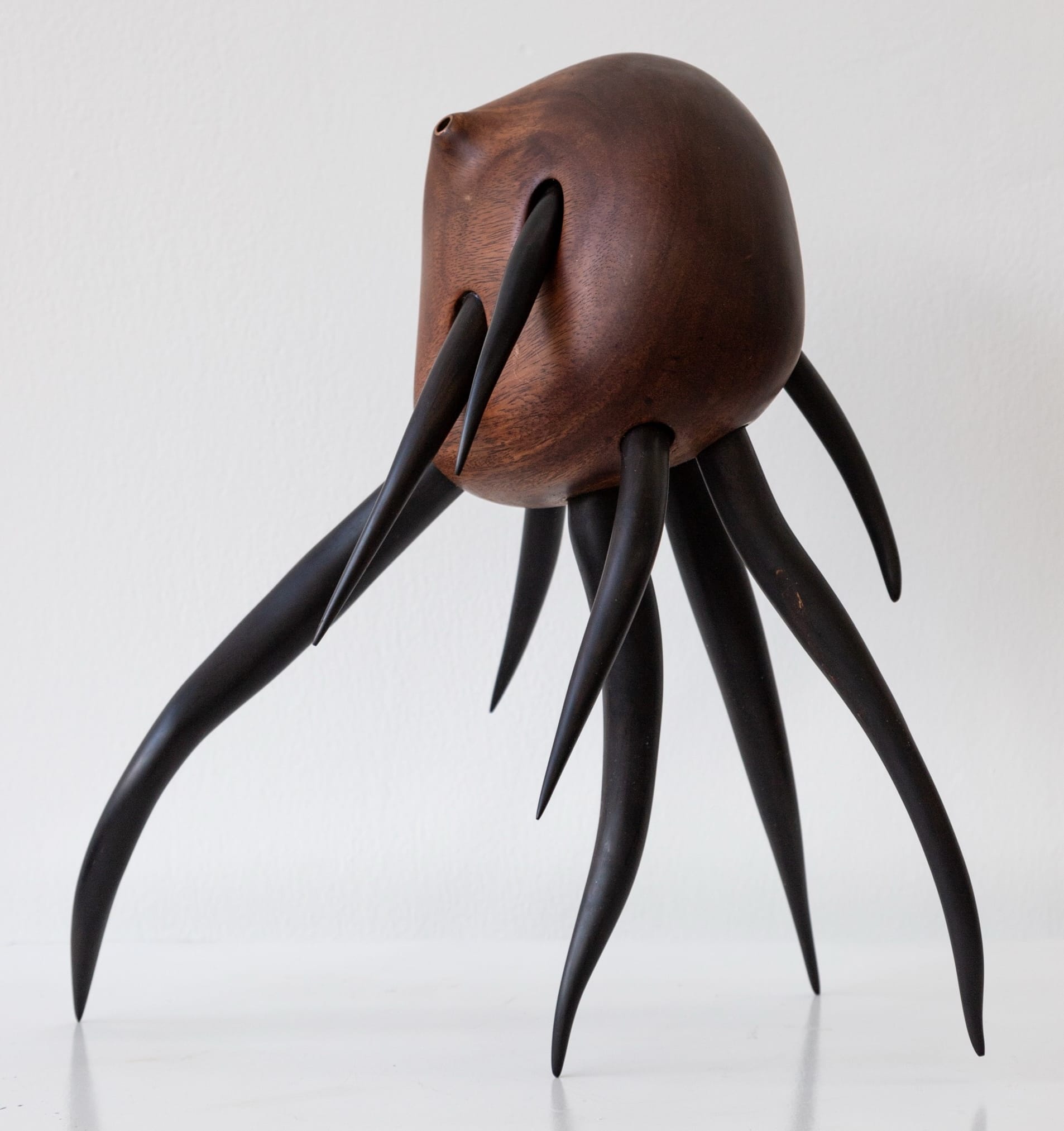 a wooden sculpture by Donald Wasswa with an abstract, sea creature-like form with long tentacles