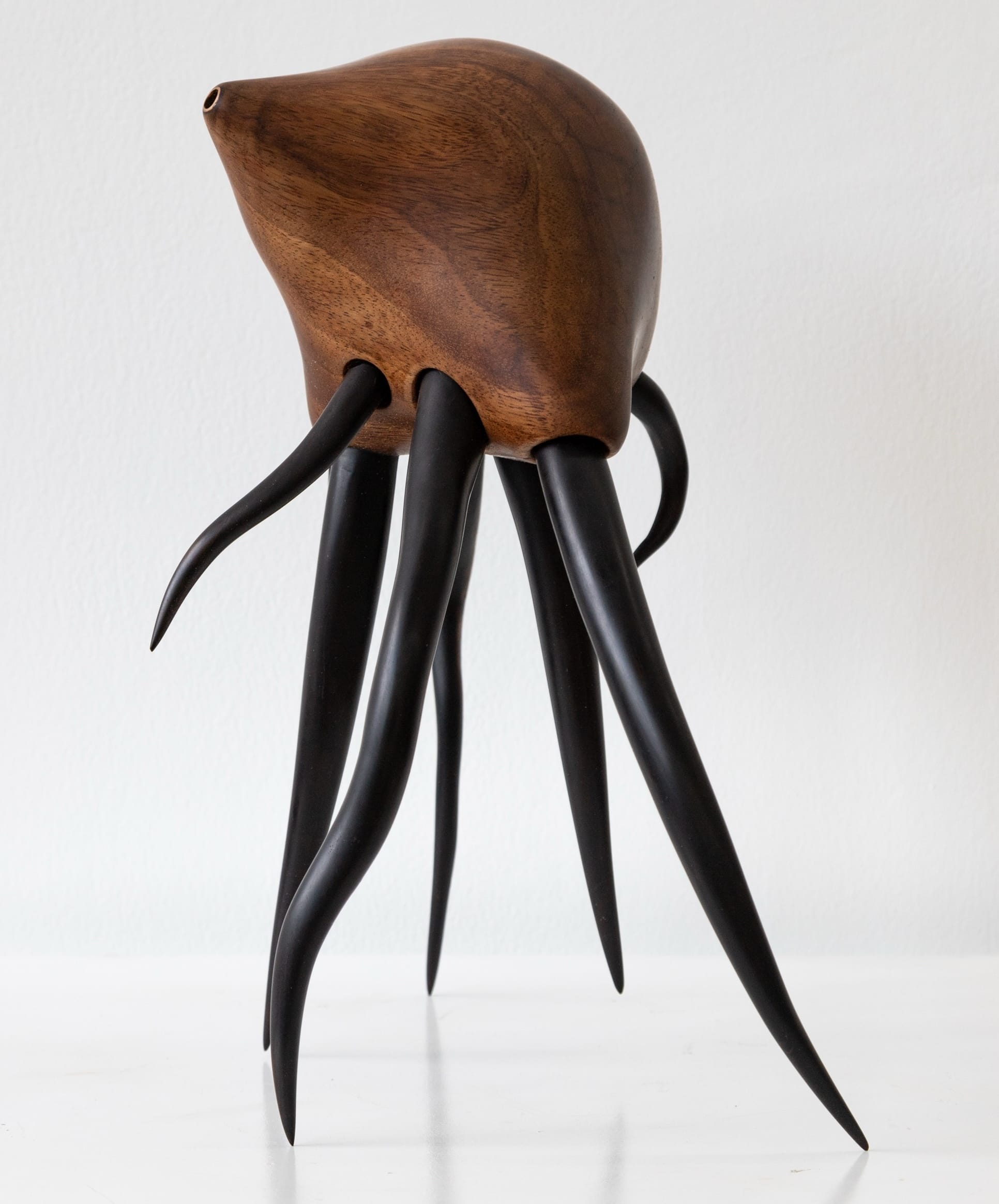 a wooden sculpture by Donald Wasswa with an abstract, sea creature-like form with long tentacles