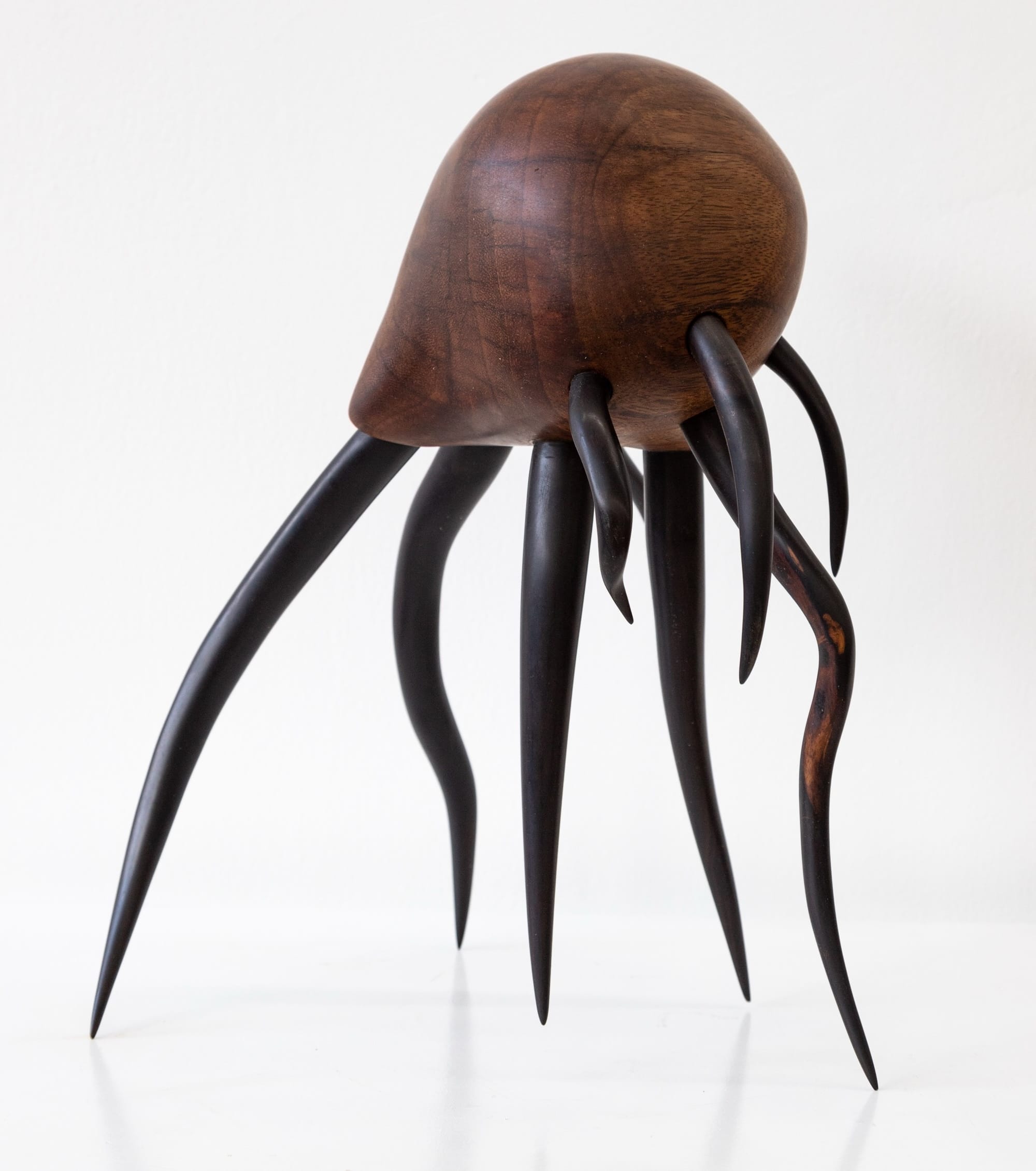 a wooden sculpture by Donald Wasswa with an abstract, sea creature-like form with long tentacles