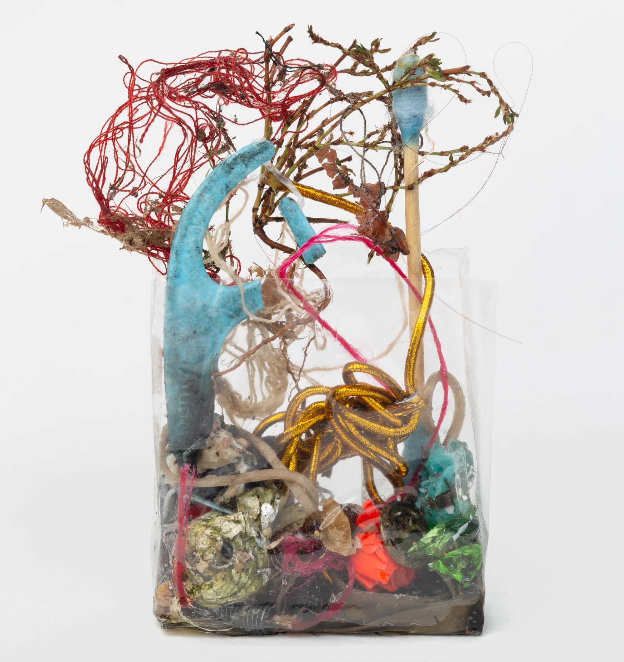 wire, plastic strings, wrappers, and other refuse in a clear plastic cellophane wrapper