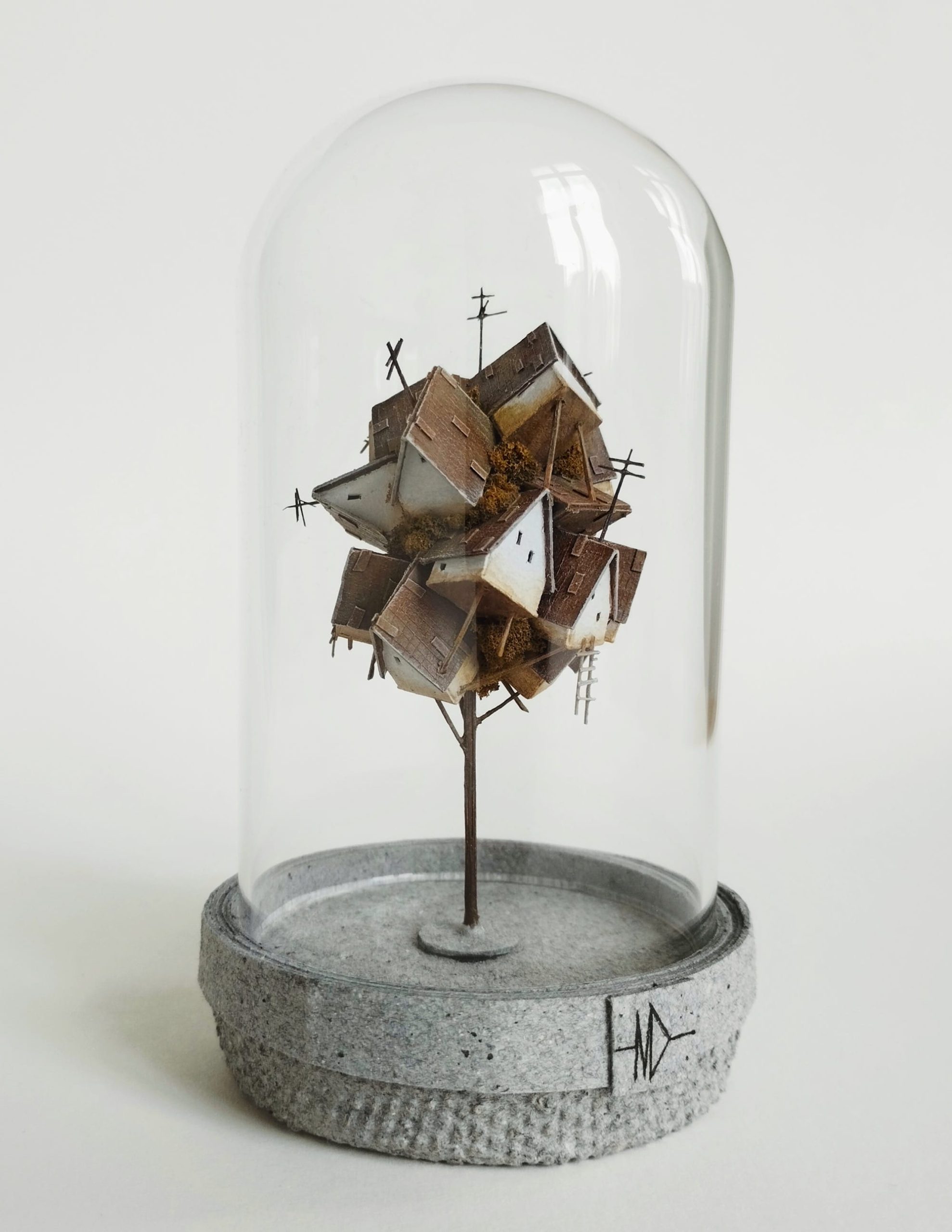 a miniature sculpture by Michael Davydov of a jumble of tiny houses and trees inside of a glass dome