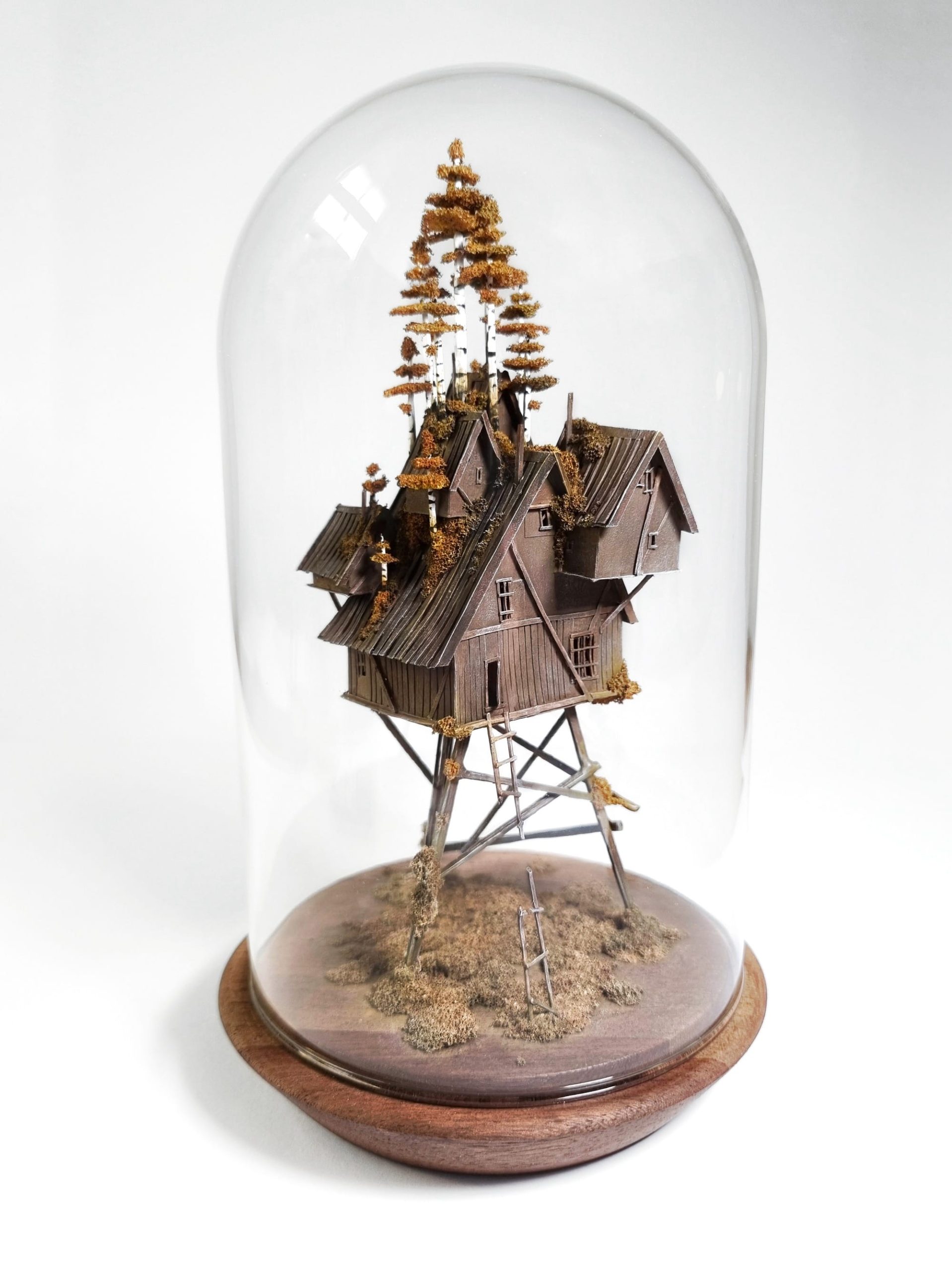 a miniature sculpture by Michael Davydov of a stack of tiny houses inside of a glass dome
