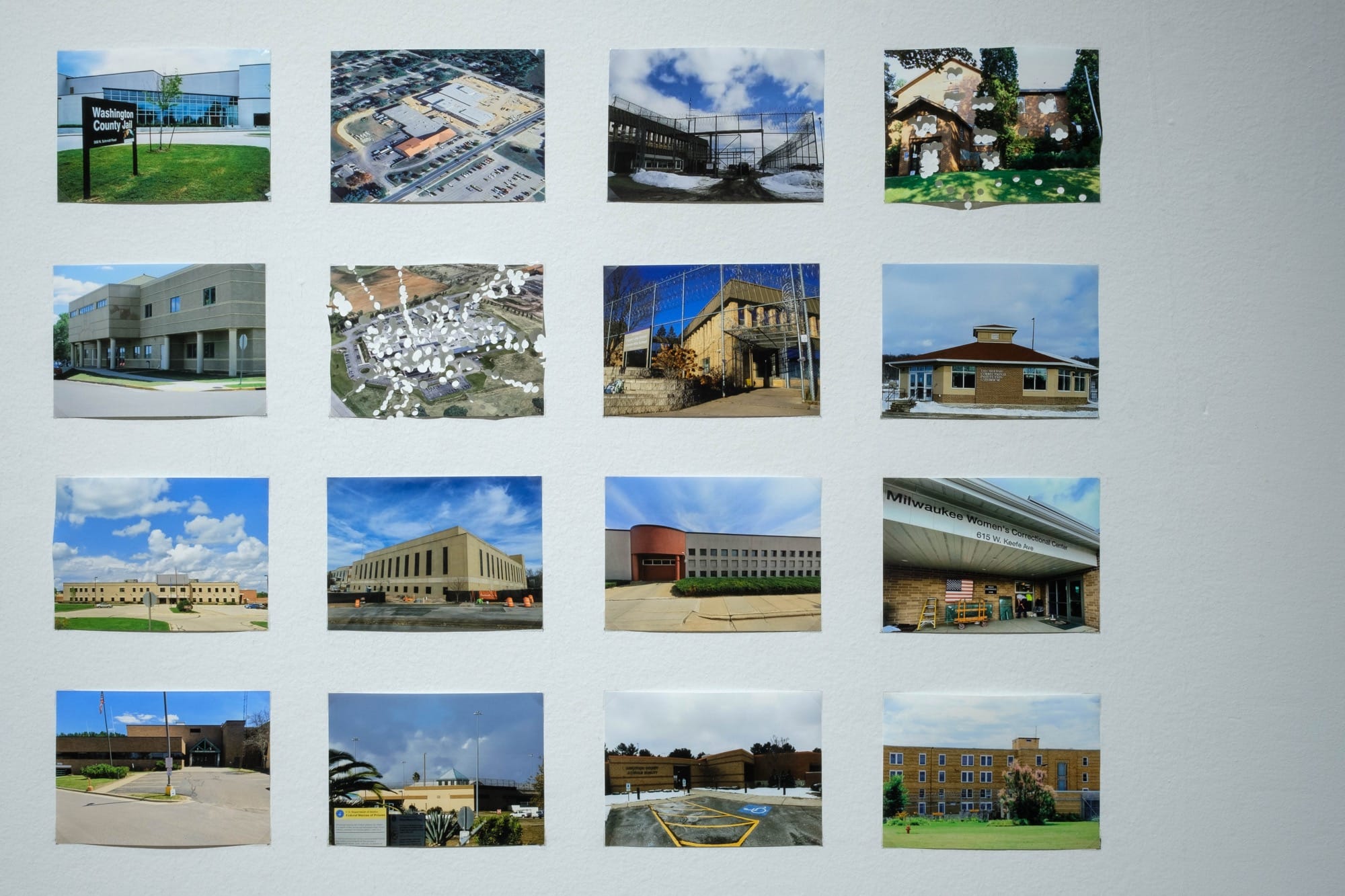 a grid of photos of buildings. some are riddled with hole punches in a detail view of an installation by Maria Gaspar in a gallery at the Haggerty Museum of Art