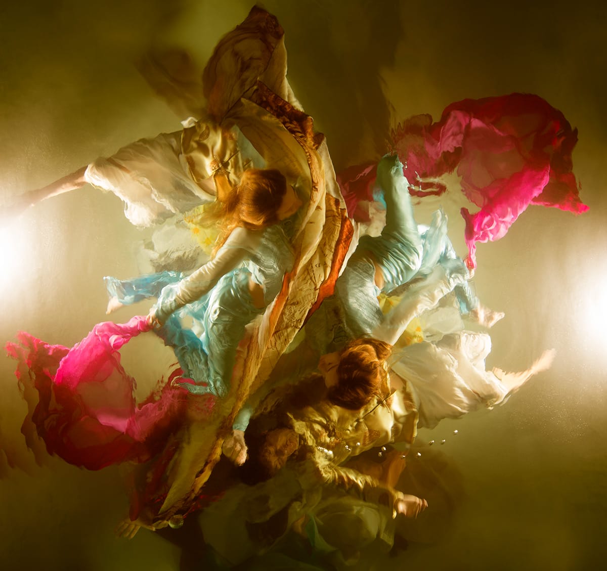 an underwater photograph by Christy Lee Rogers of figures enveloped in billowing fabric