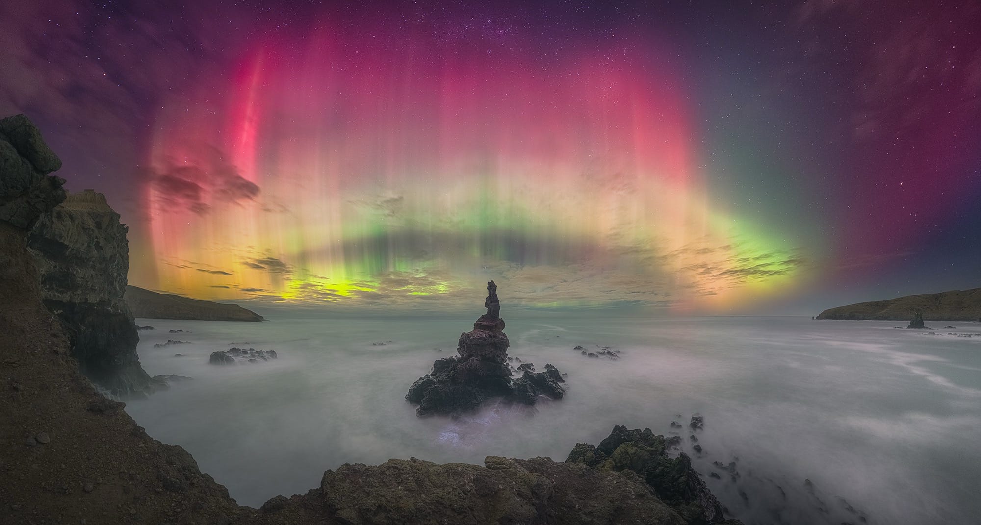 the Northern Lights over a watery, rocky landscape