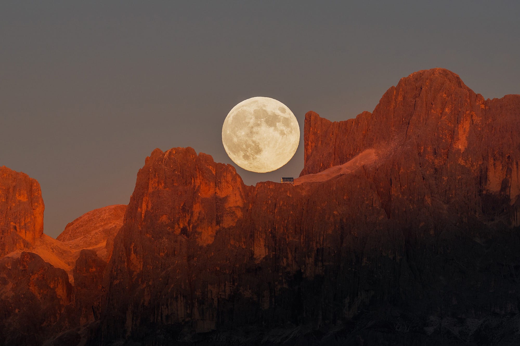 the moon photographed above a Dolomite mountain ridge