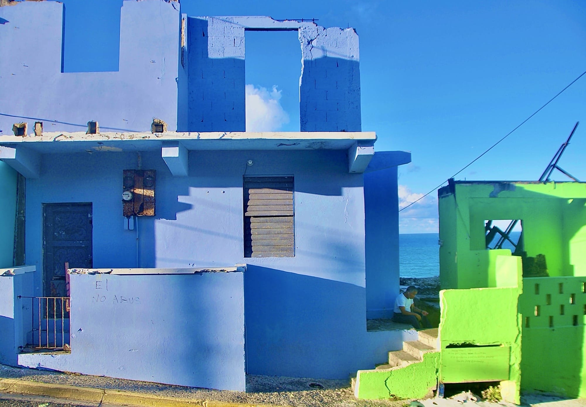 a photograph by Ruben Natal-San Miguel of a blue-painted home on the Puerto Rico coast