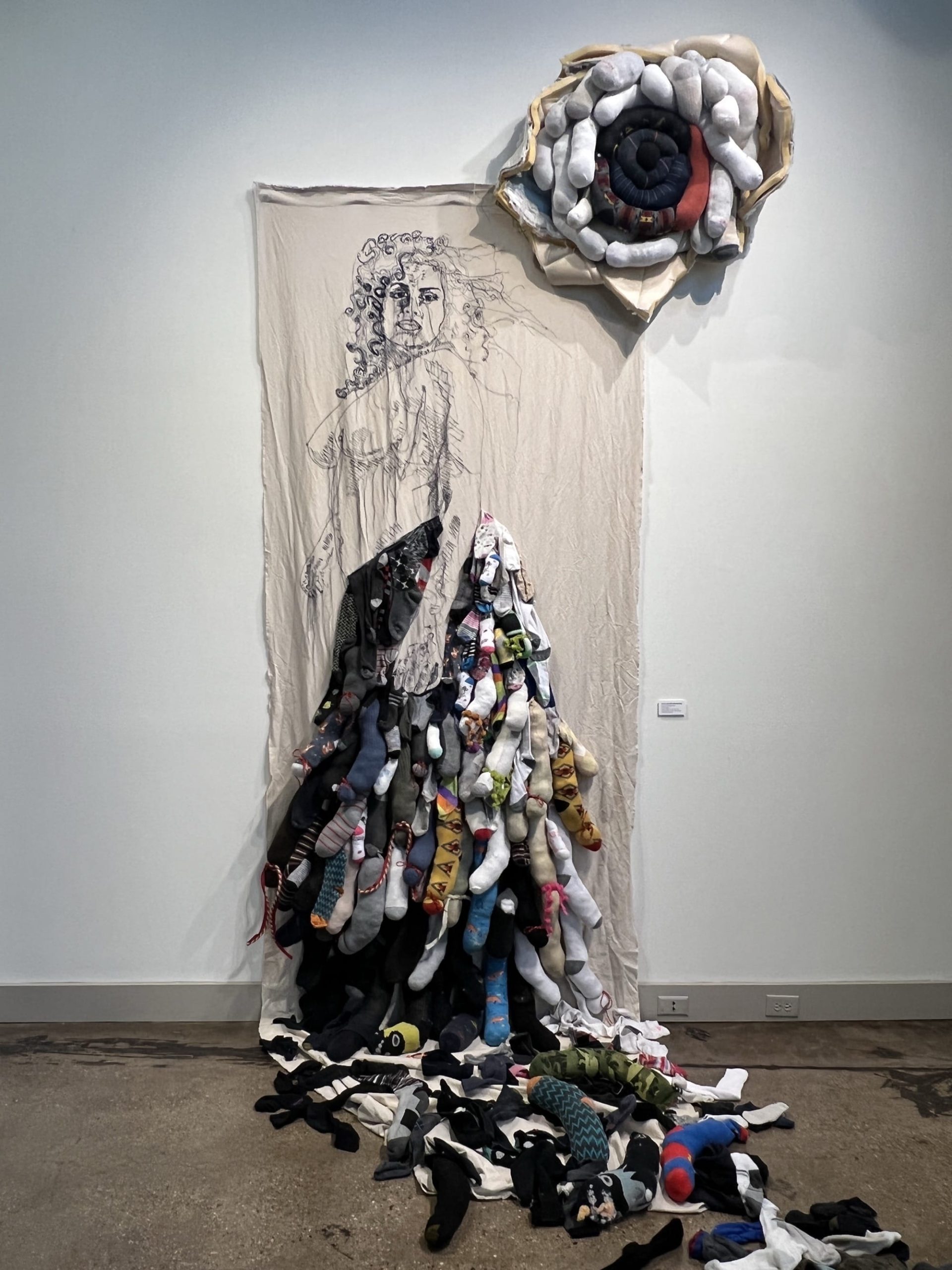 a textile wall installation by Elsa María Meléndez of a woman with a flowing dress of patterned fabric shapes