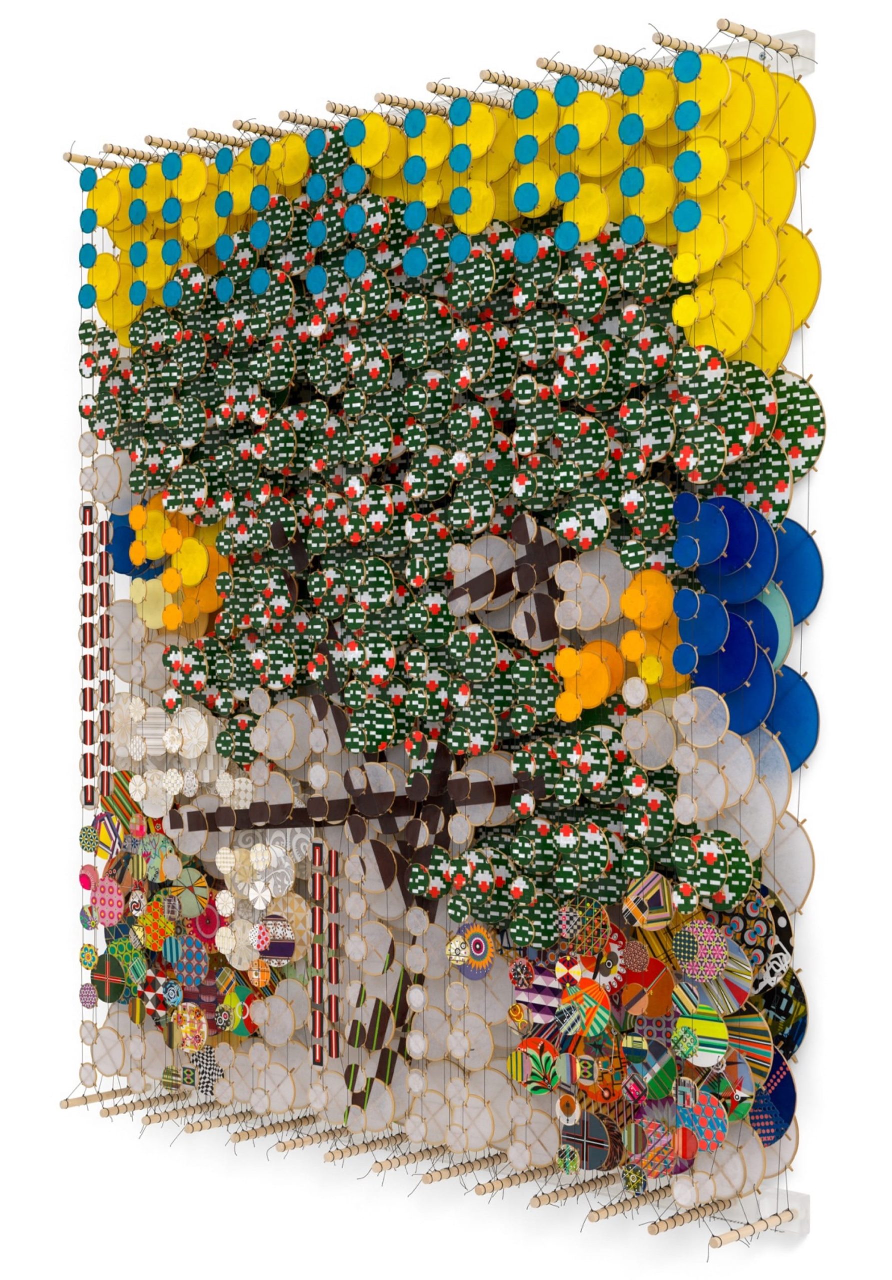 an oblique view of an abstract artwork by Jacob Hashimoto made from twine and numerous colorful, patterned paper discs installed in rows for a layered effect