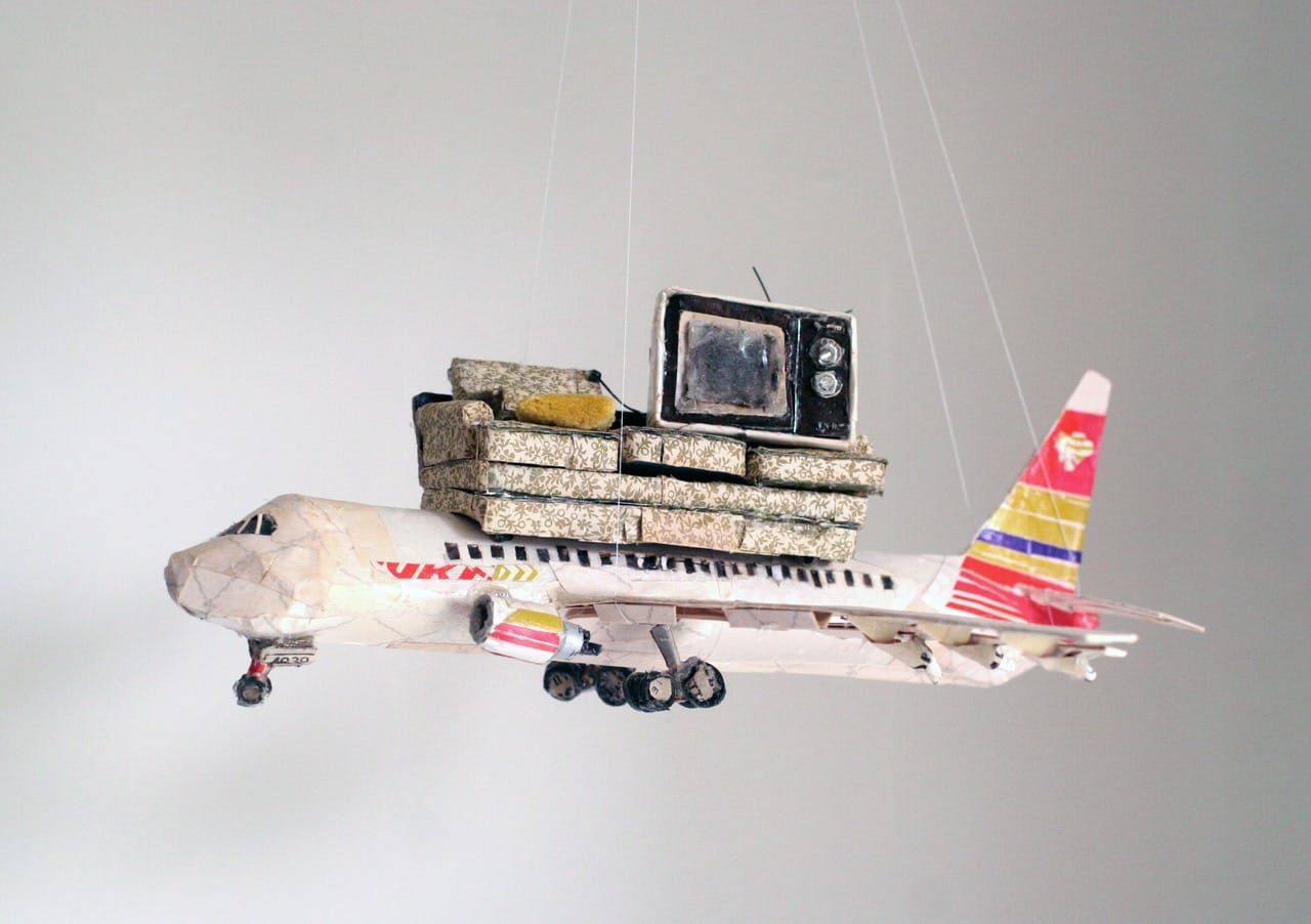 an airplane carrying a couch and tv set made from found scraps by Lydia Ricci