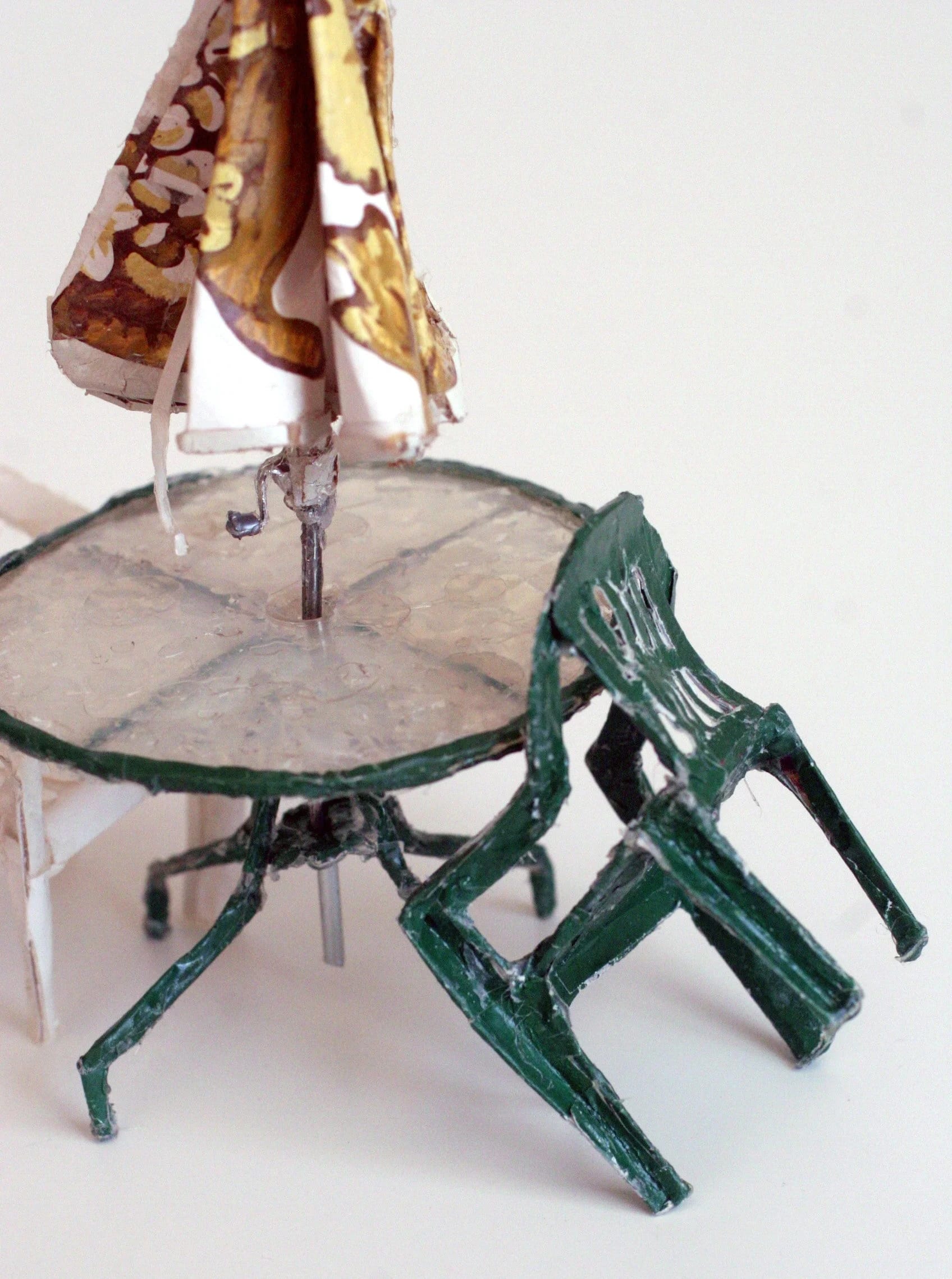 an outdoor table and chair with an umbrella made from found scraps by Lydia Ricci